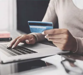 photo of a person holding a credit card and typing on a laptop